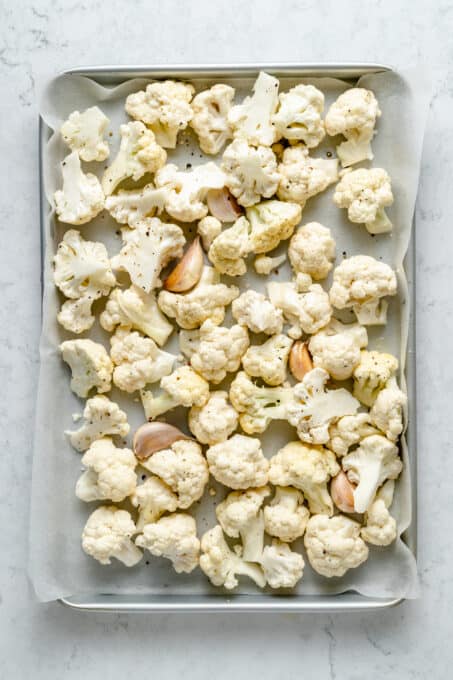 Cauliflower and garlic on parchment-lined baking sheet
