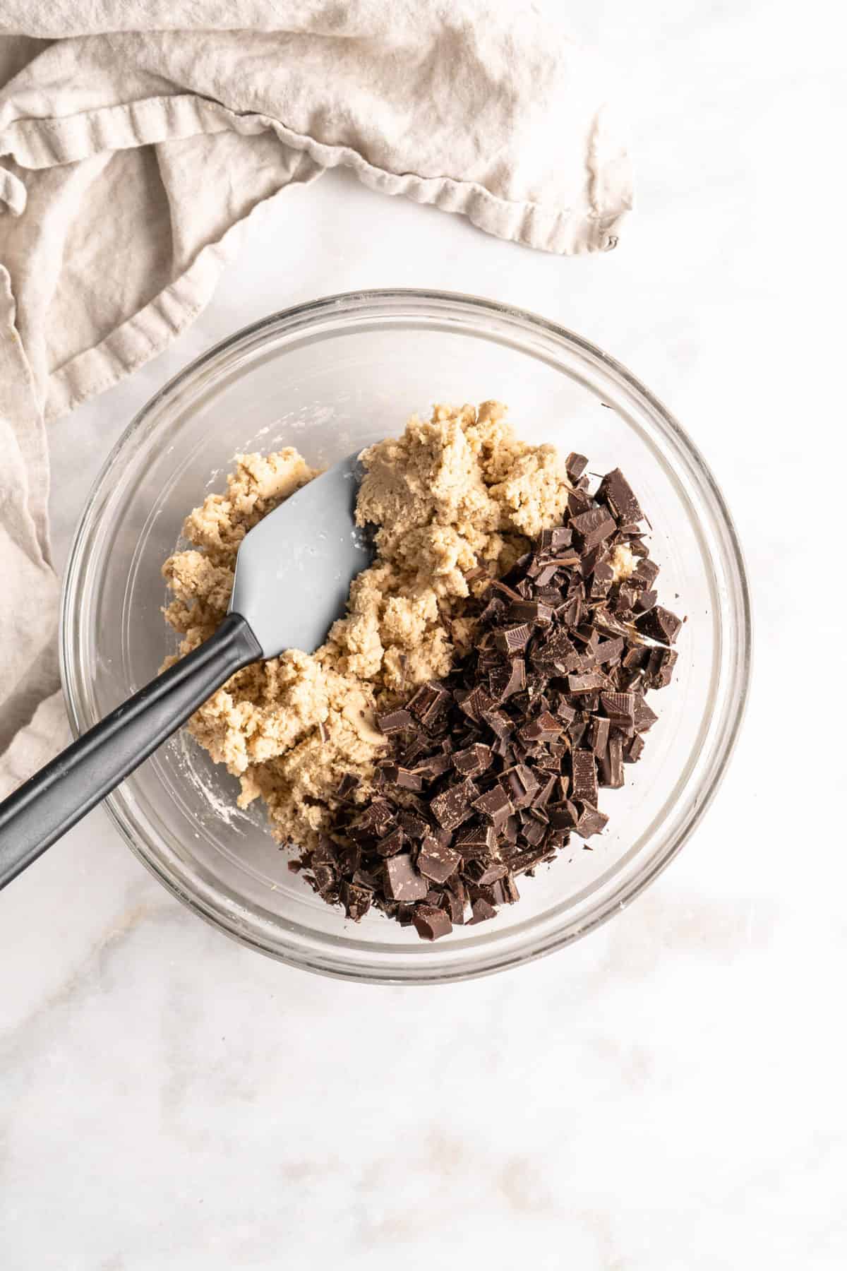 Cookie dough and chocolate chunks in glass bowl with spatula