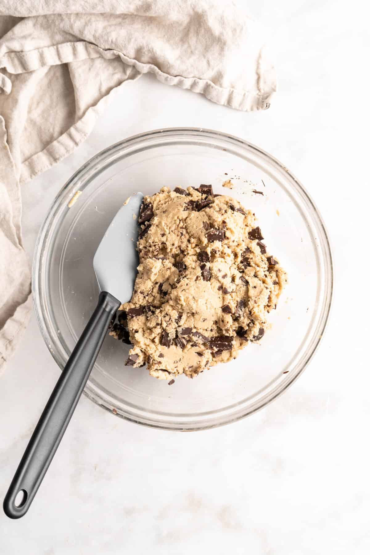 Chocolate chip cookie dough in glass bowl with spatula