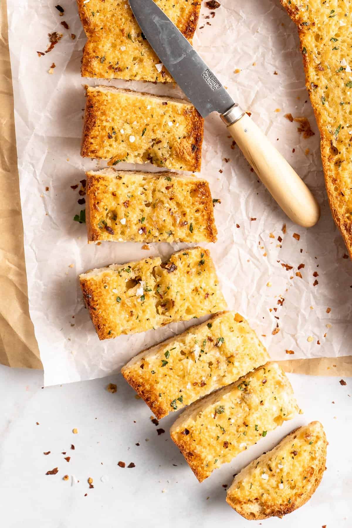Garlic bread sliced into pieces with knife