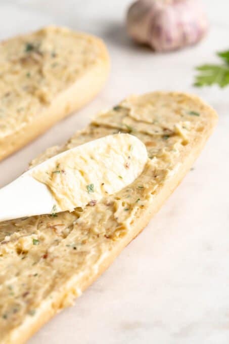 Smearing garlic butter onto baguette