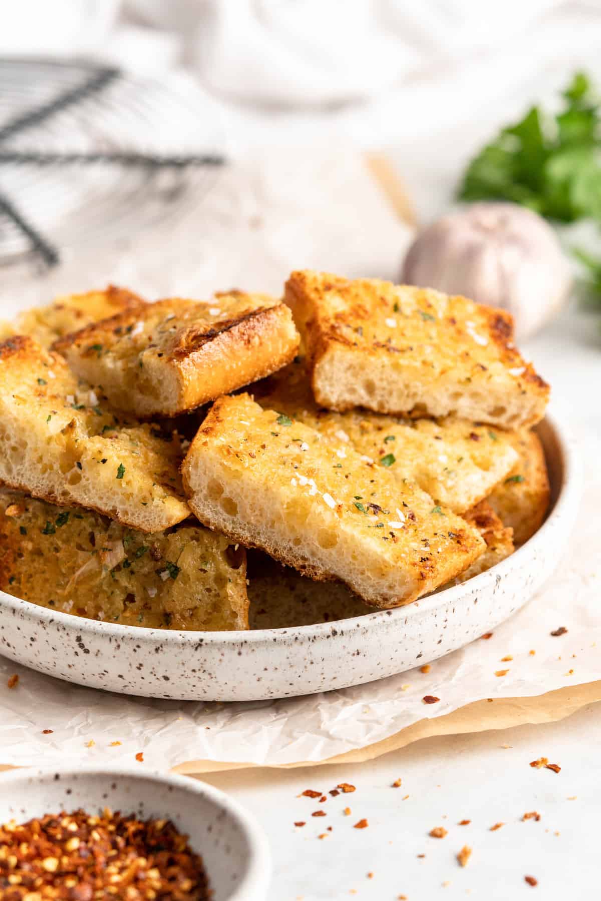 Pieces of roasted garlic bread stacked in rustic bowl