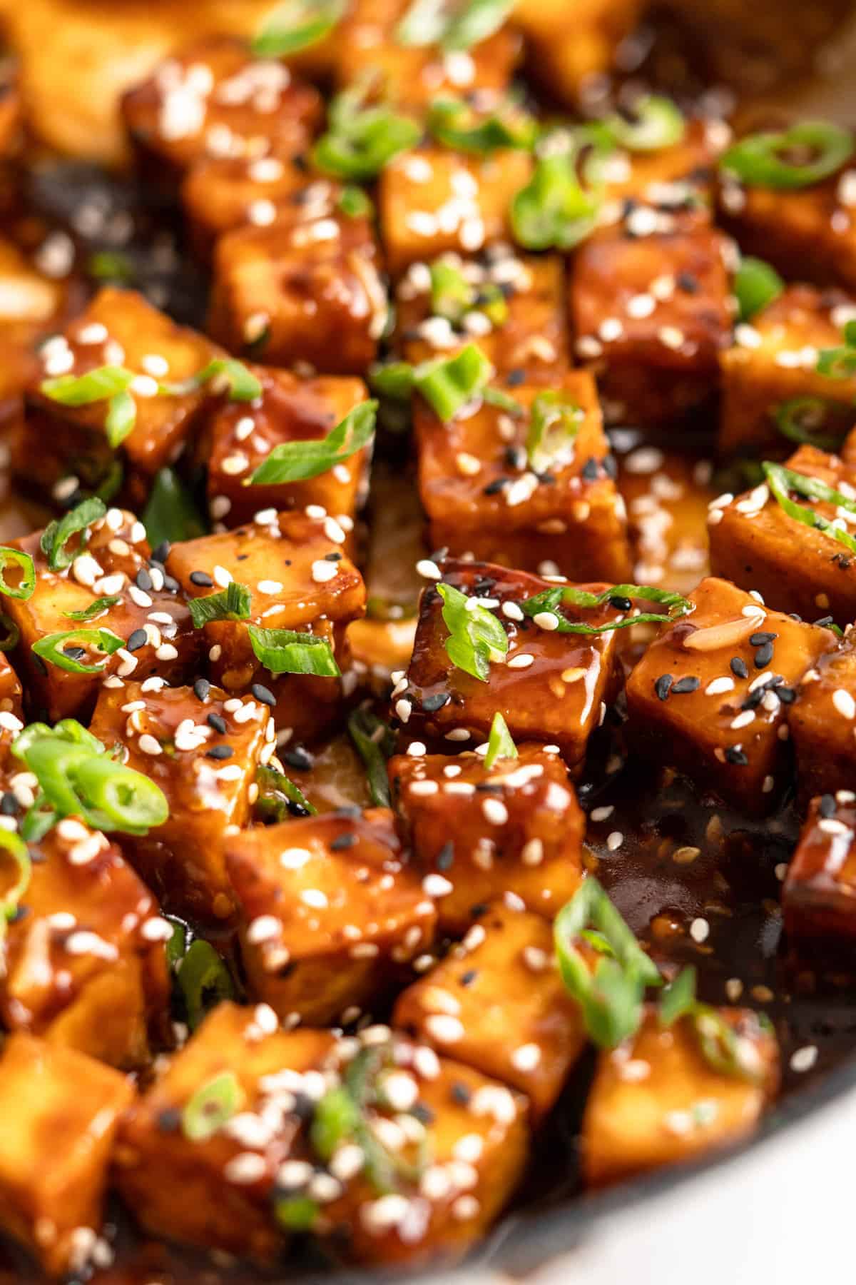 Closeup of General Tso Tofu topped with sesame seeds and scallions