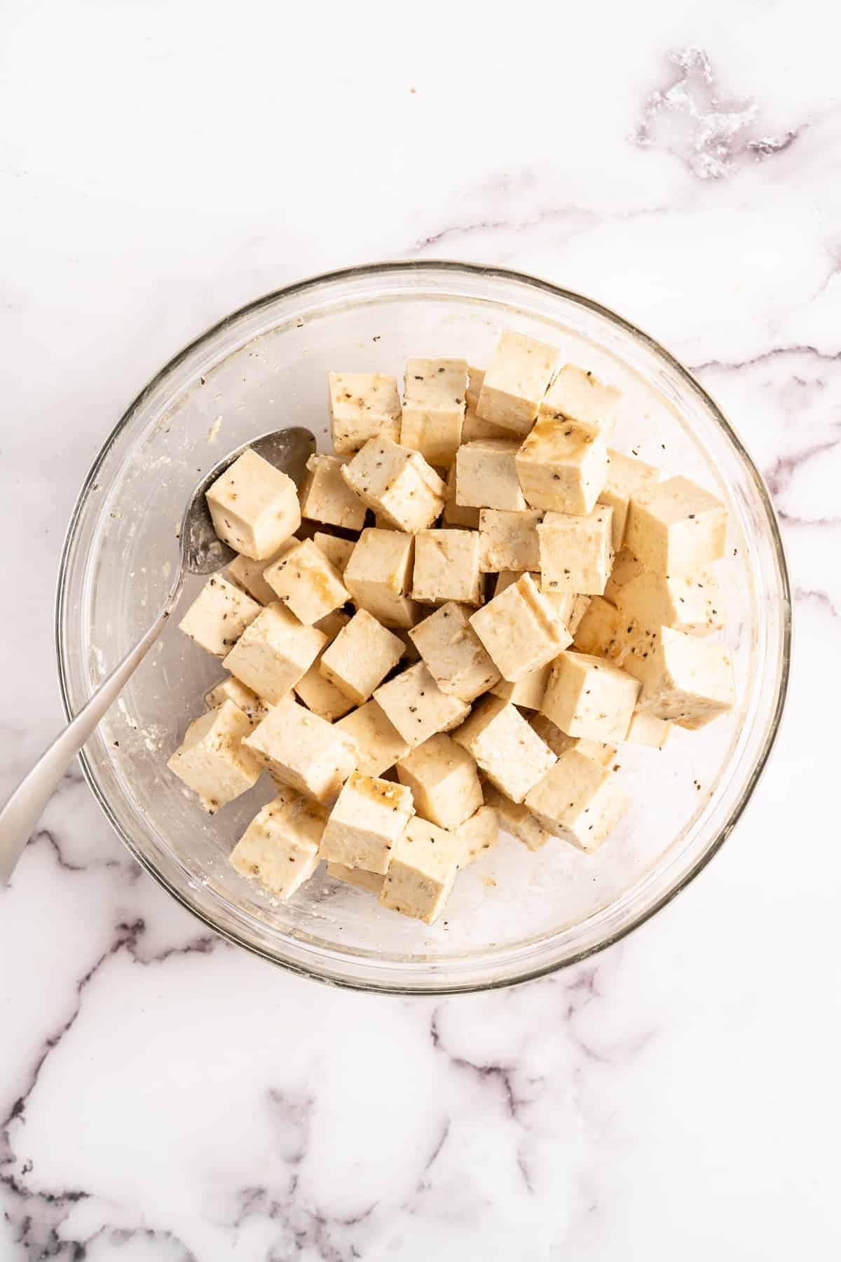 Tofu being coated in glass mixing bowl