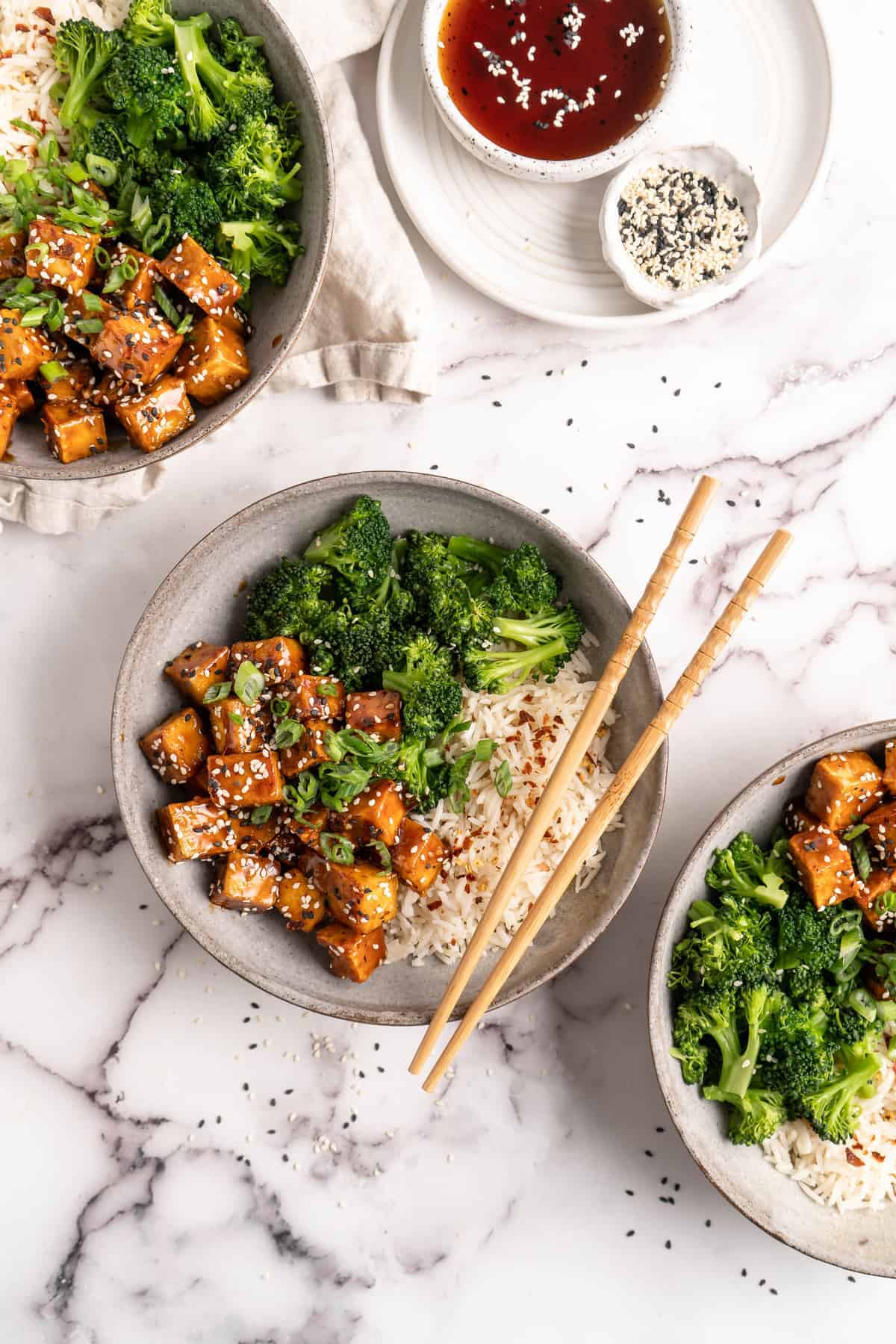 Three bowls of General Tso Tofu with white rice and broccoli