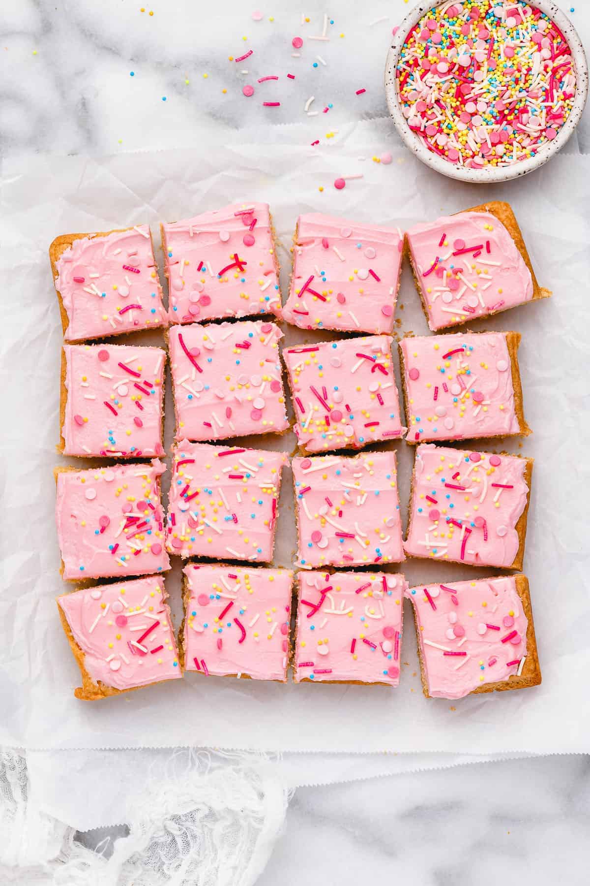 Overhead view of cut sugar cookie bars with bowl of sprinkles