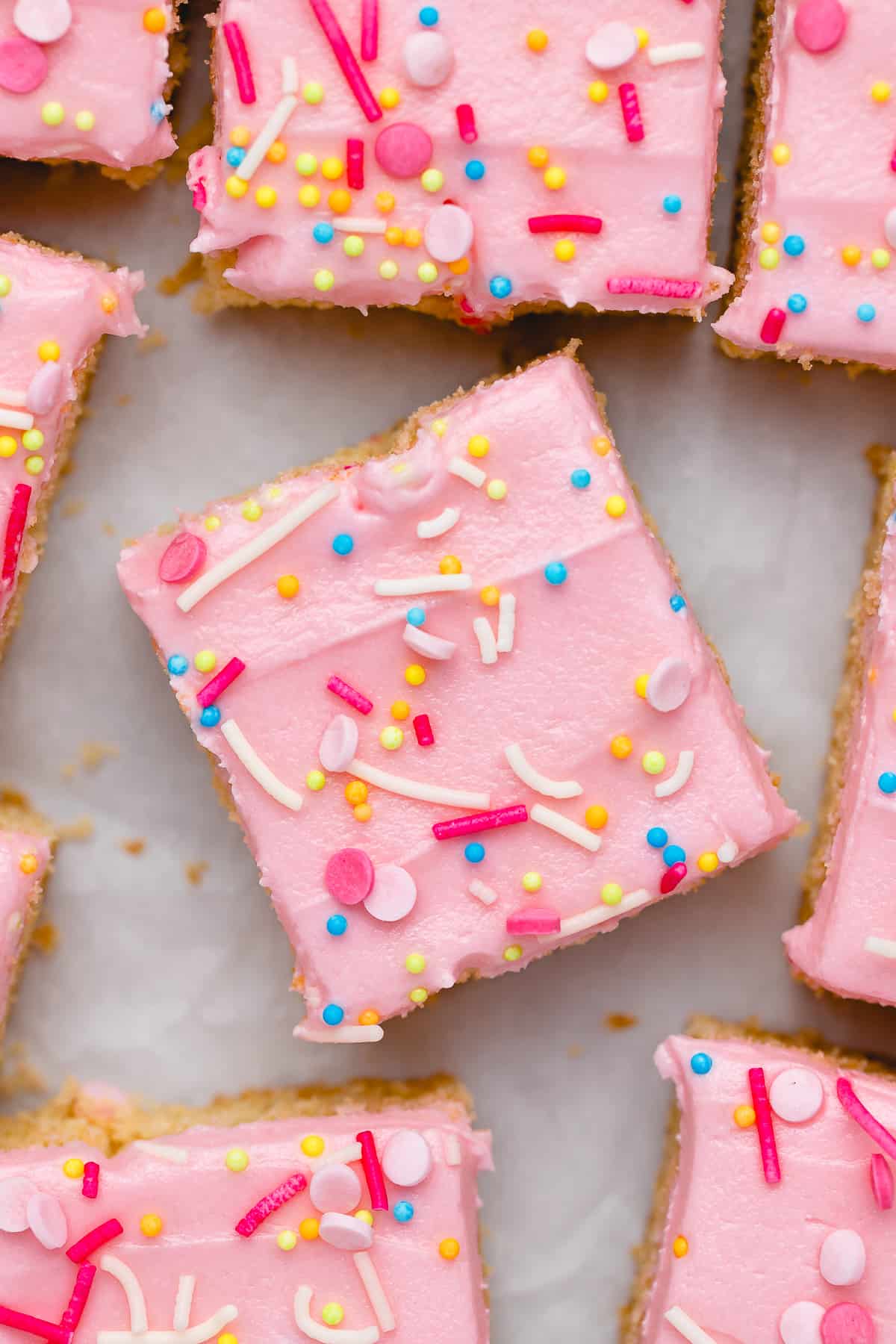 Overhead view of sugar cookie bars topped with pink frosting and sprinkles