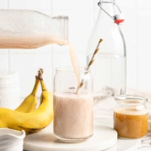 Banana milk being poured into jar with straw