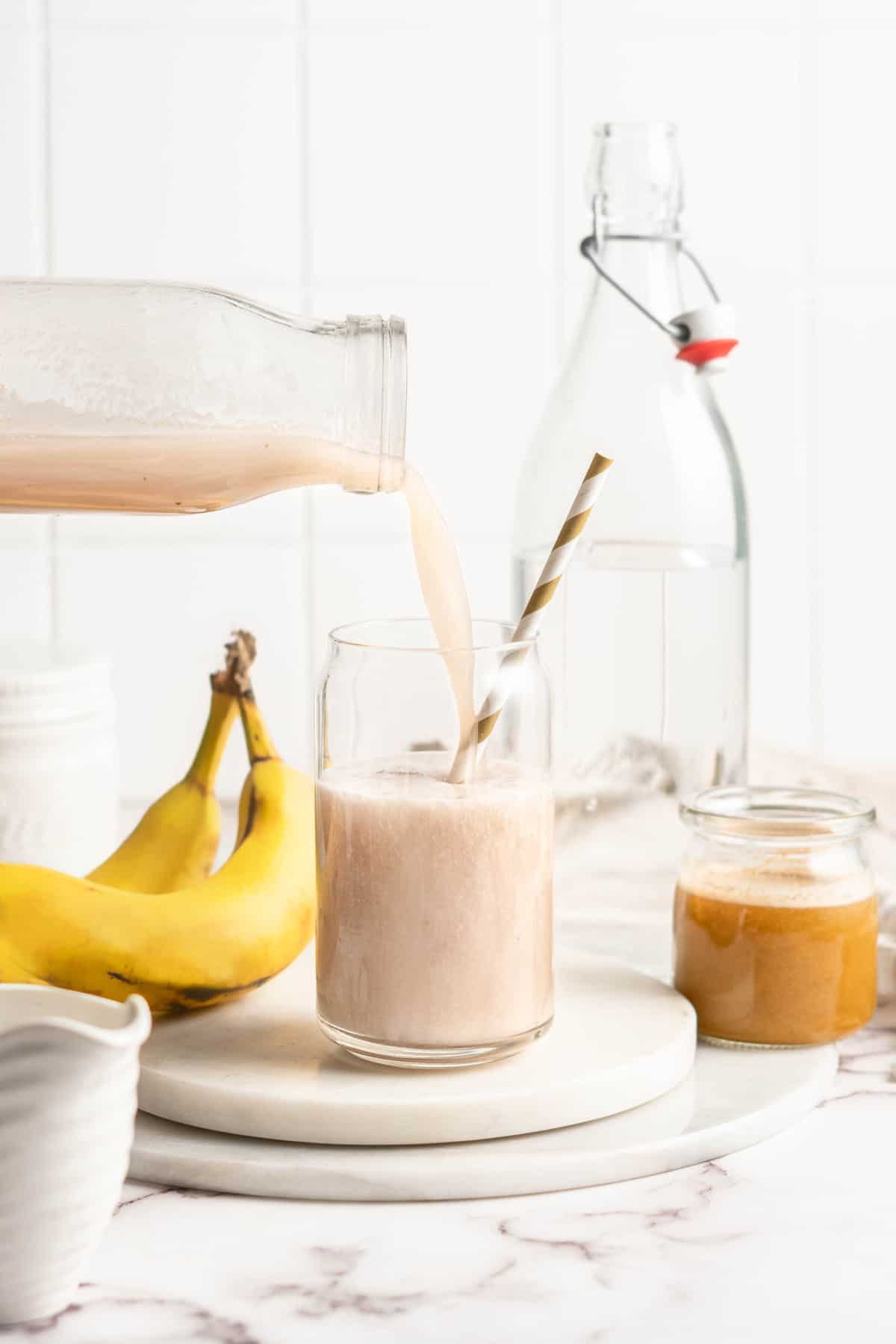 Banana milk being poured into jar with straw
