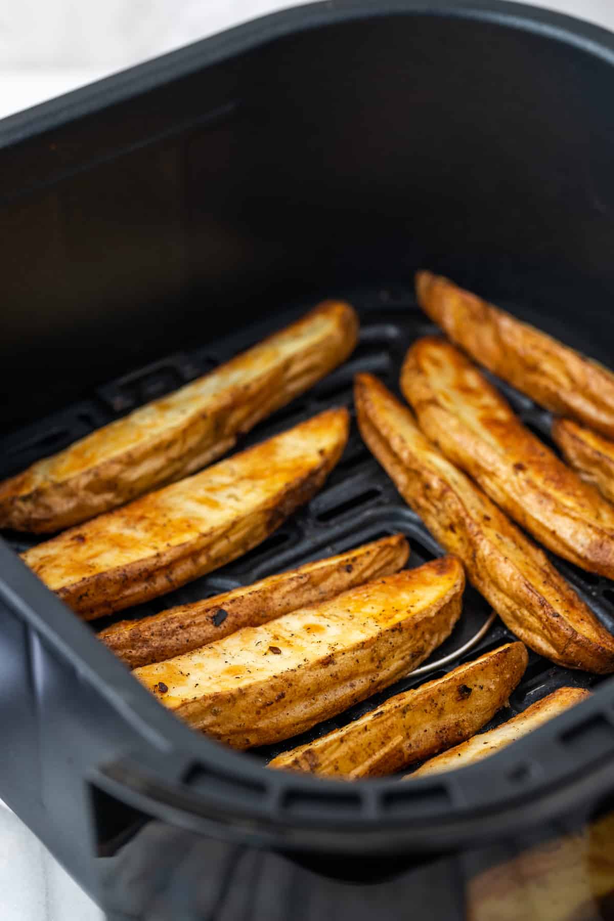 Cooked potato wedges in the air fryer basket