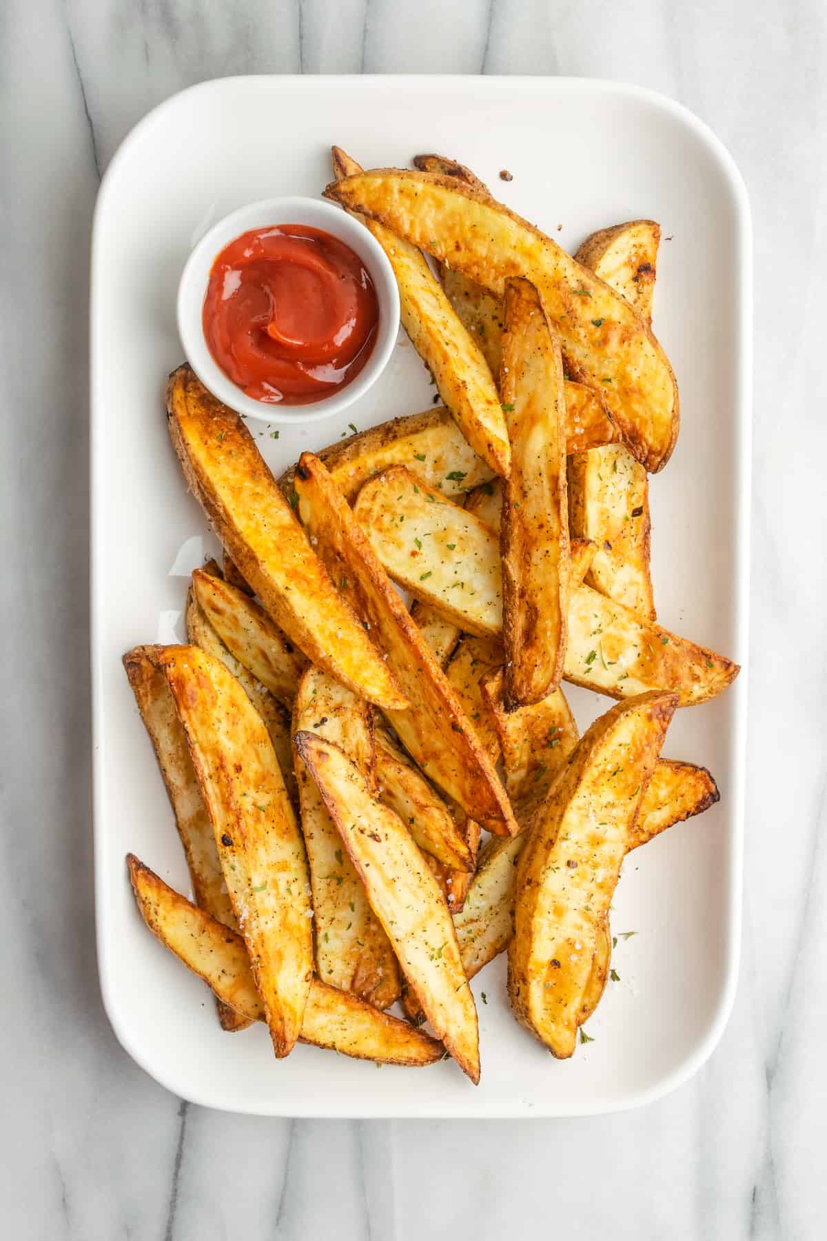 A plate of potato wedges with a ramekin of ketchup