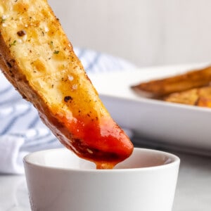 A potato wedge being dipped into ketchup
