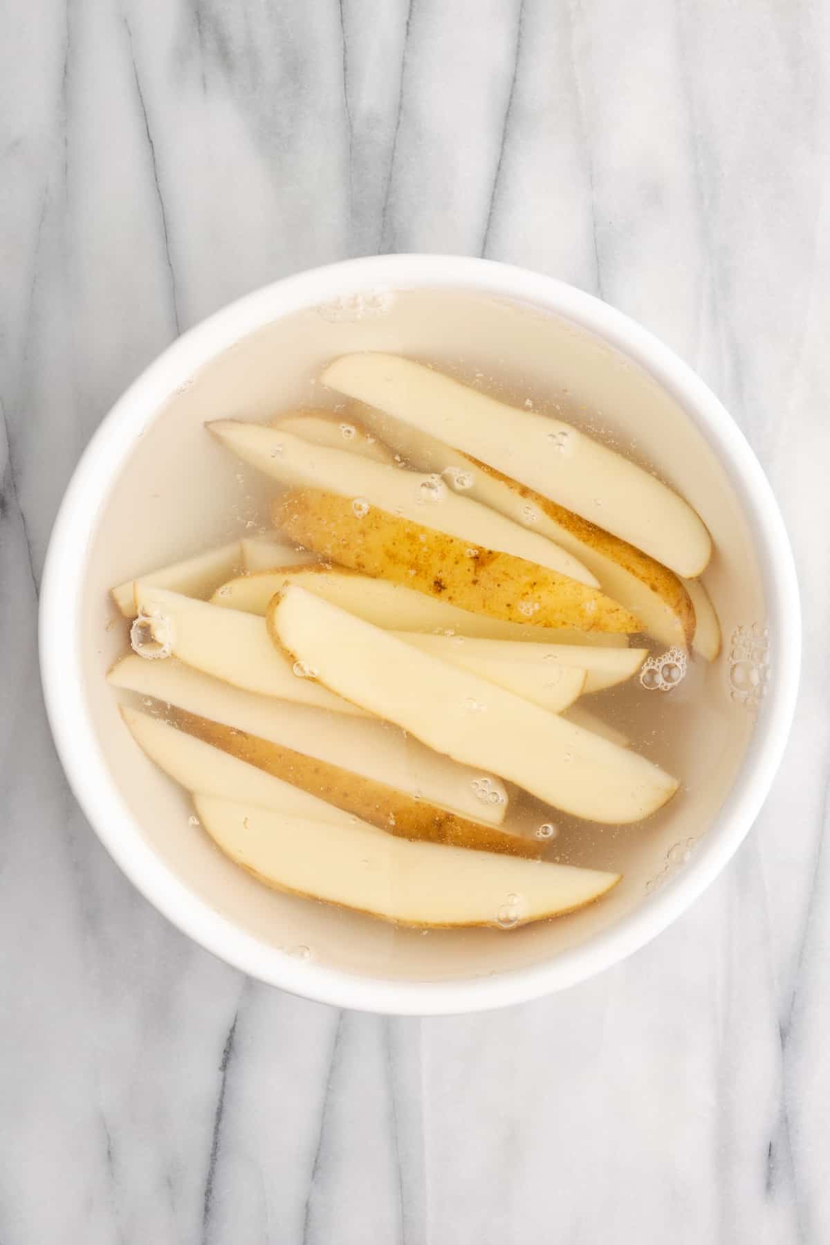 Uncooked potato wedges soaking in water