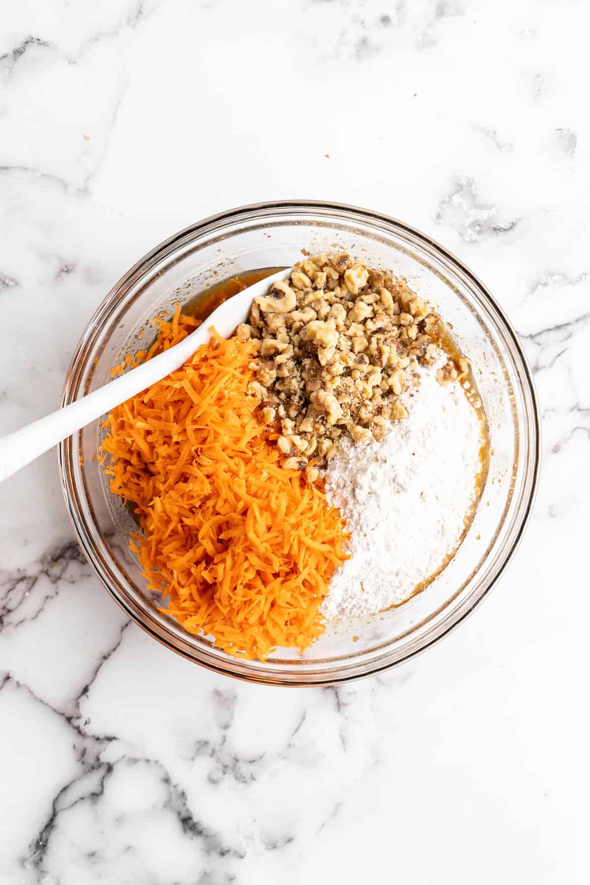 Overhead view of vegan carrot cake ingredients in glass mixing bowl