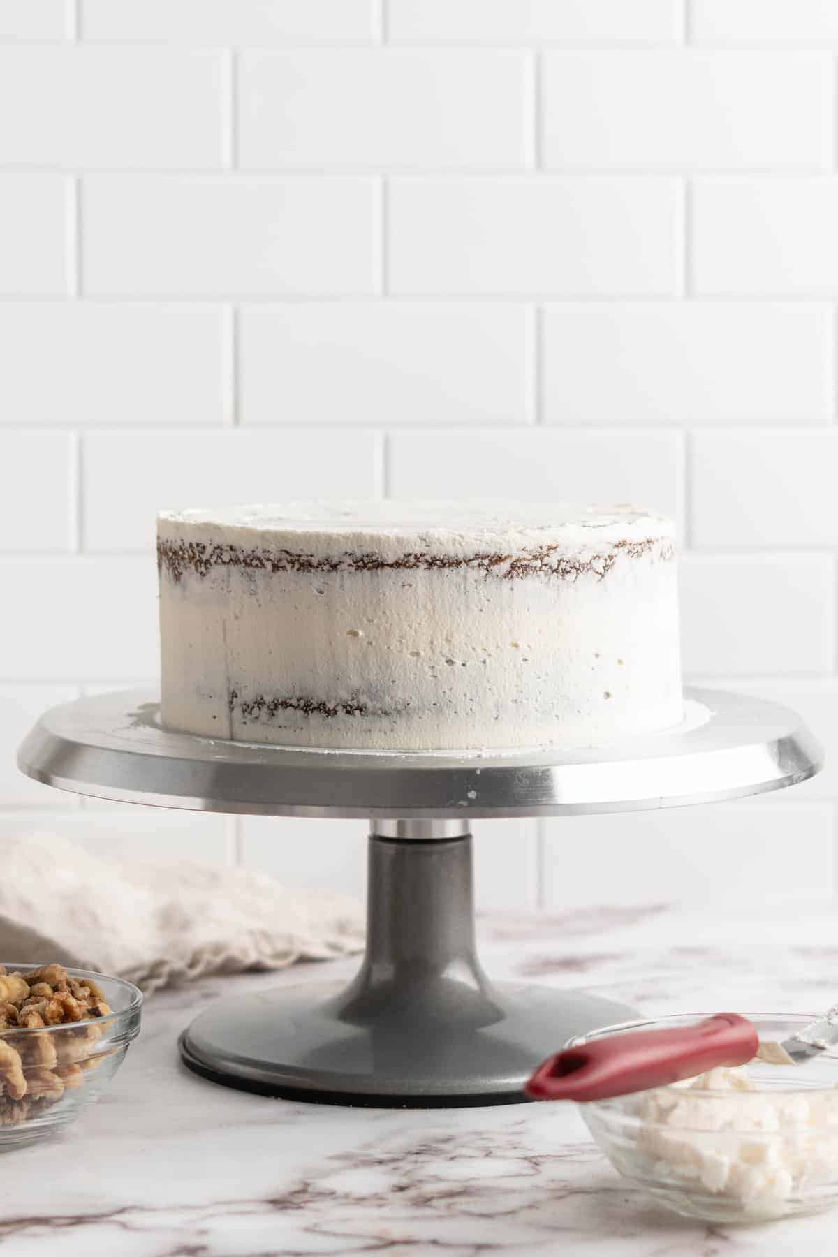 Frosting vegan carrot cake on cake stand