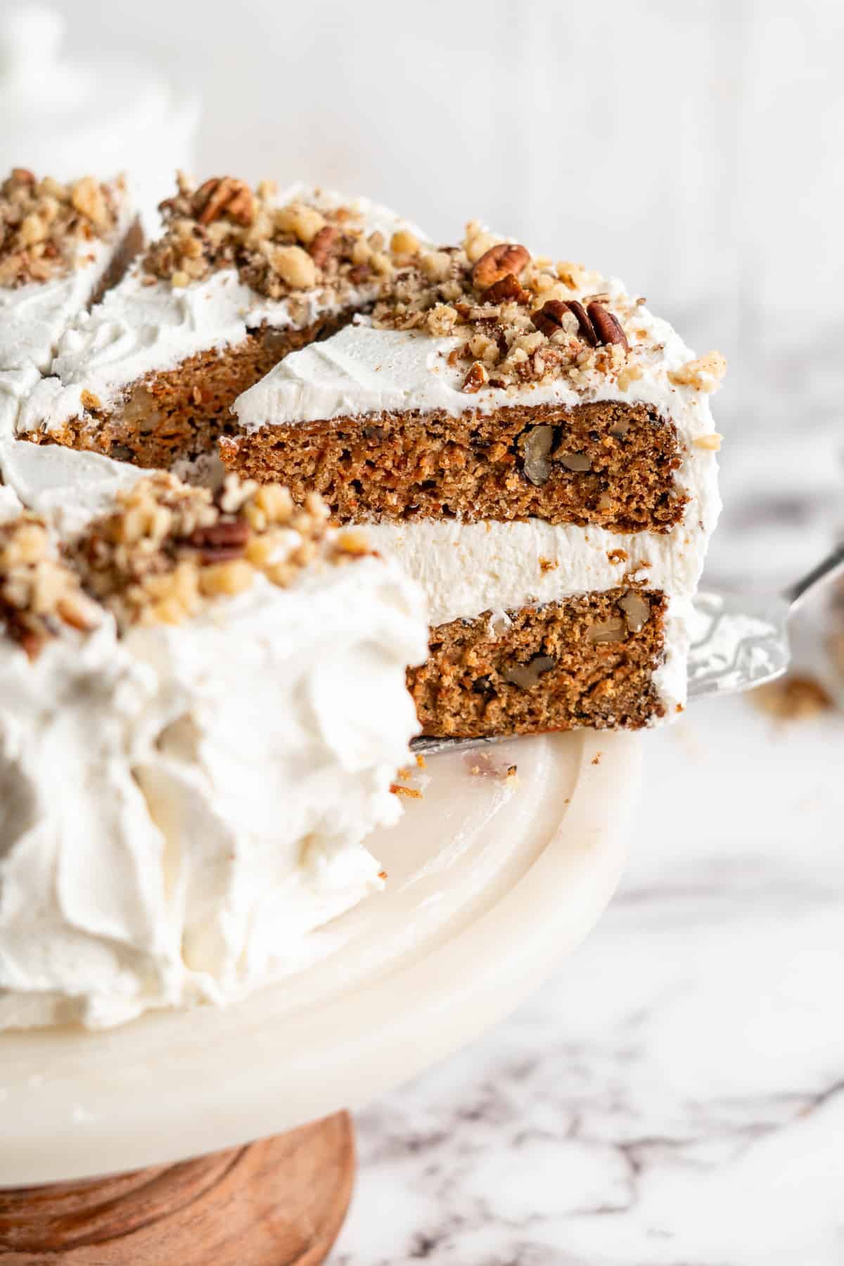 Slice of vegan carrot cake being removed from cake