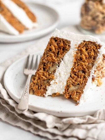 Closeup of vegan carrot cake slice on white plate with fork