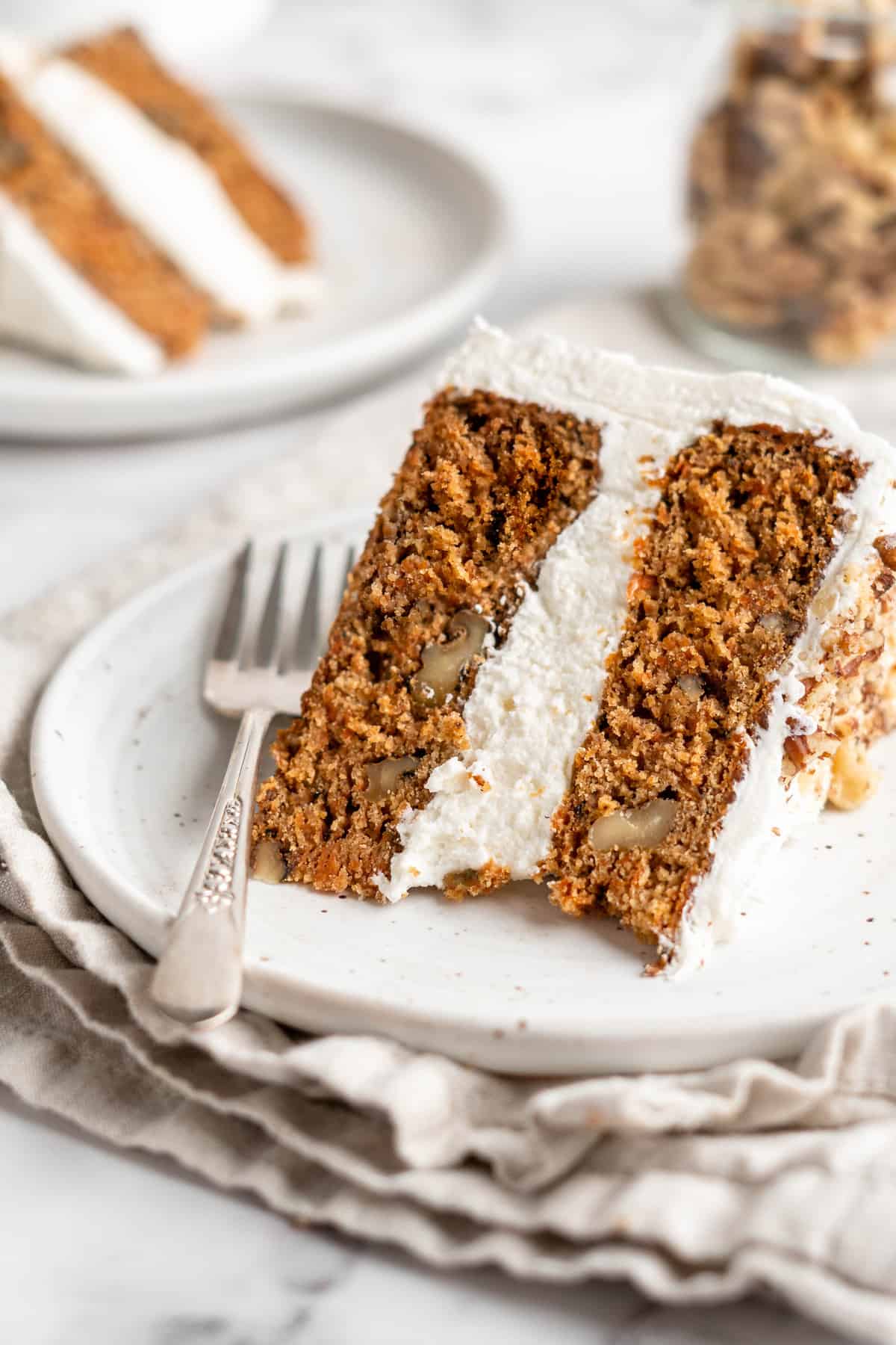 Closeup of vegan carrot cake slice on white plate with fork