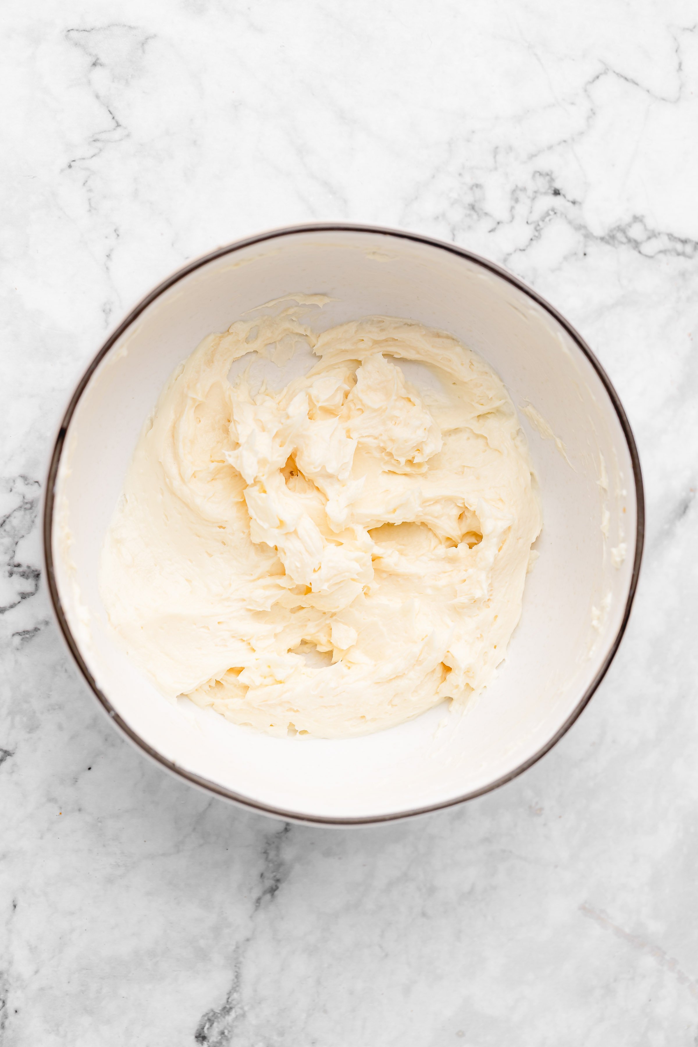 Overhead view of creamed butter and cream cheese in mixing bowl