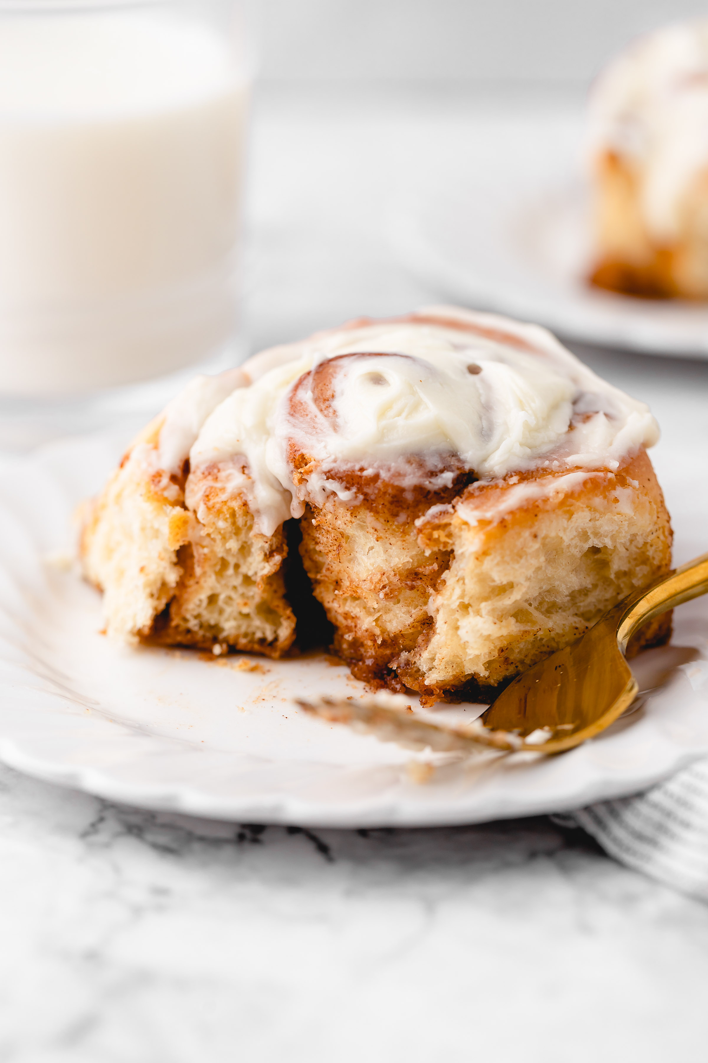 Vegan cinnamon roll on plate with corner torn off to show inside