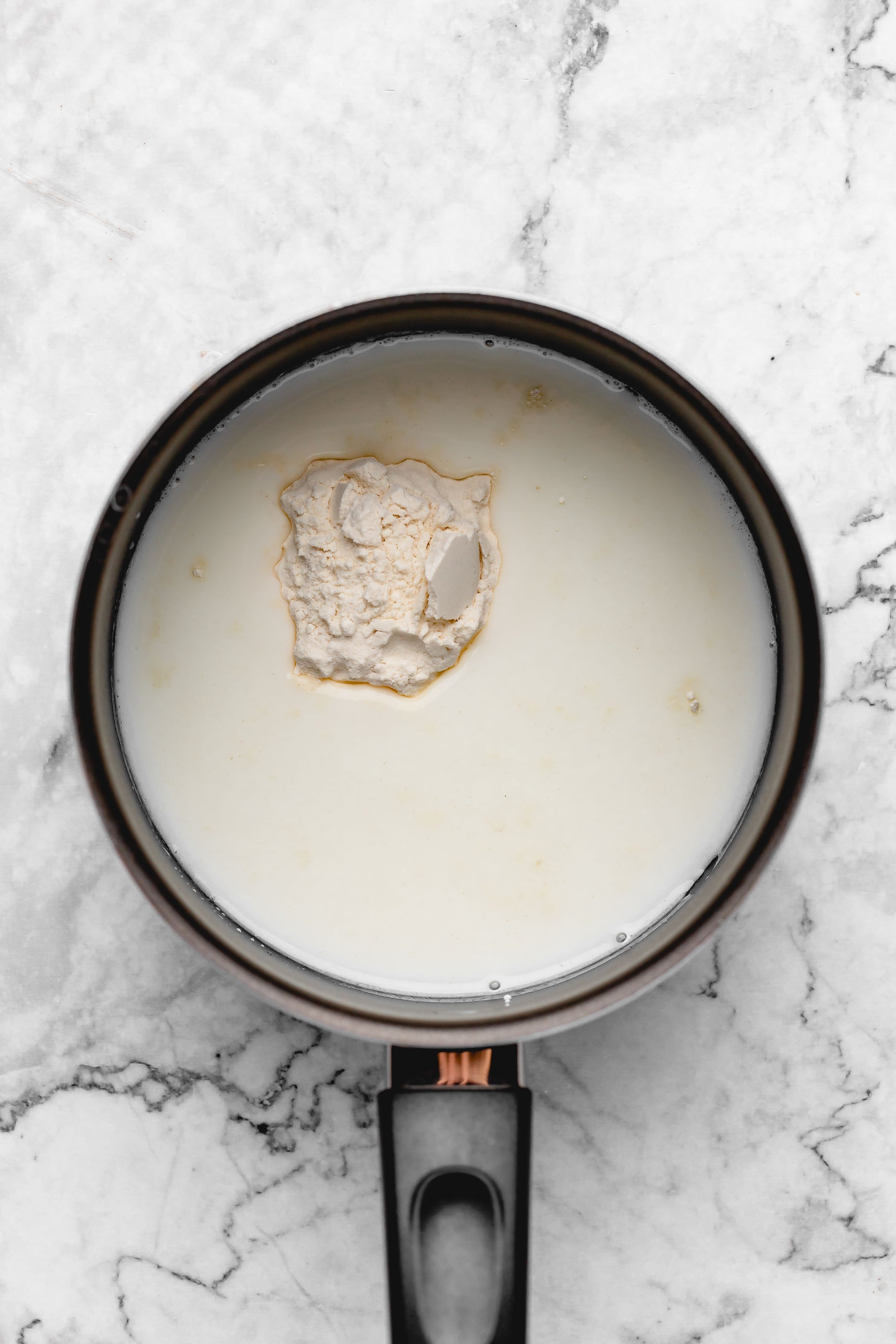 Overhead view of flour and soy milk in saucepan