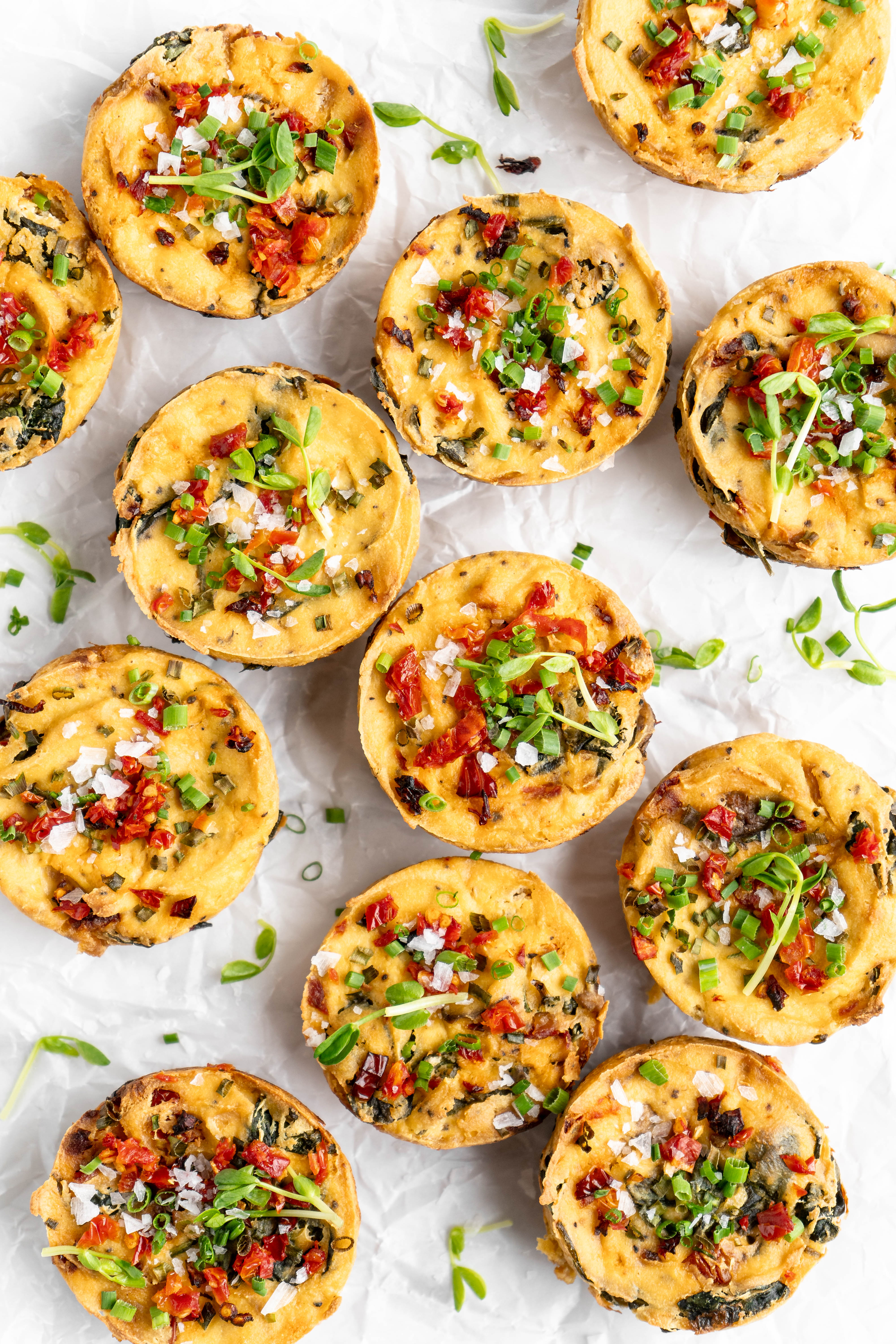 Vegan quiche muffins with garnishes on parchment paper