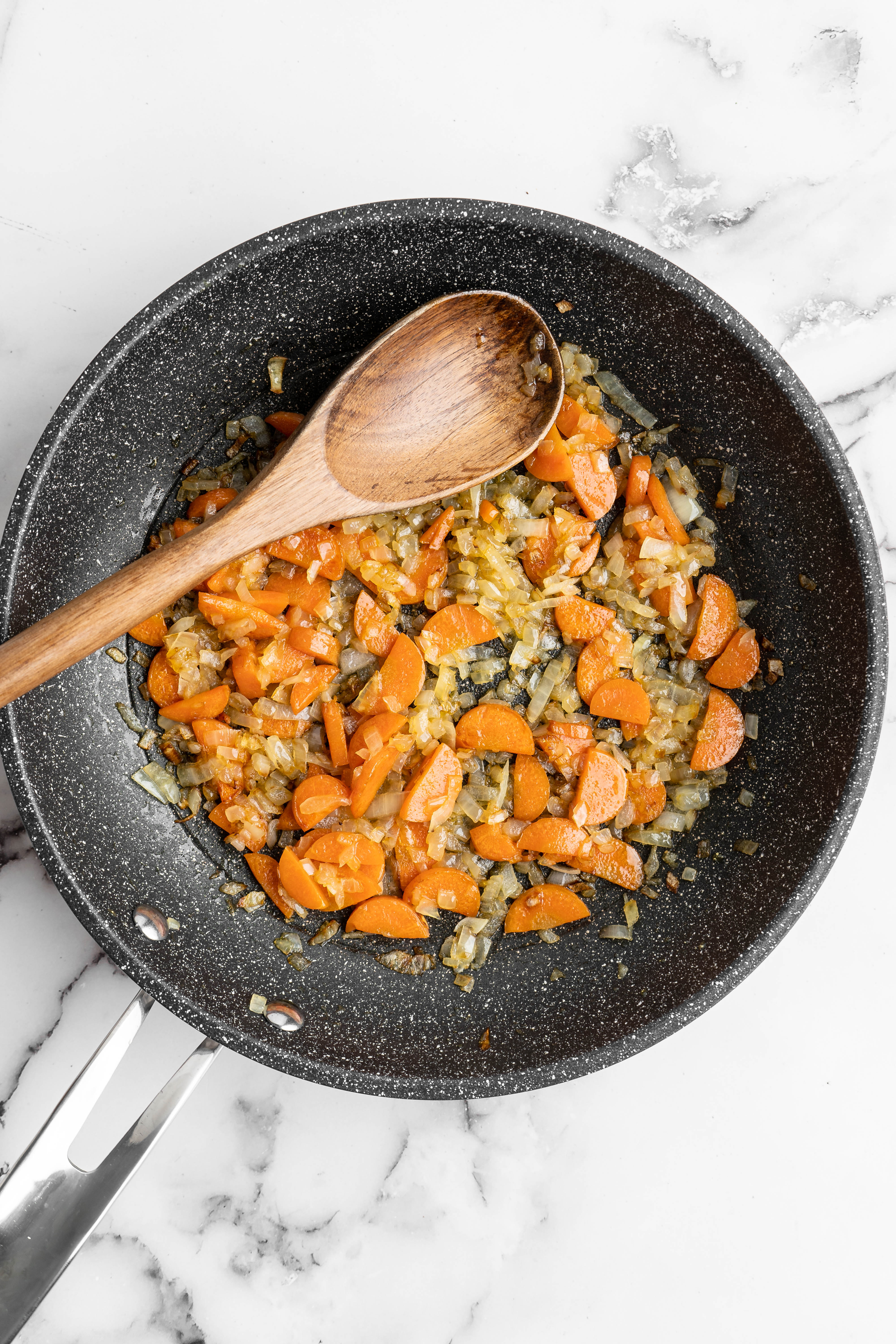 Overhead view of cooked carrots and onions in skillet