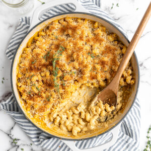 Baked vegan mac and cheese in skillet with wooden spoon