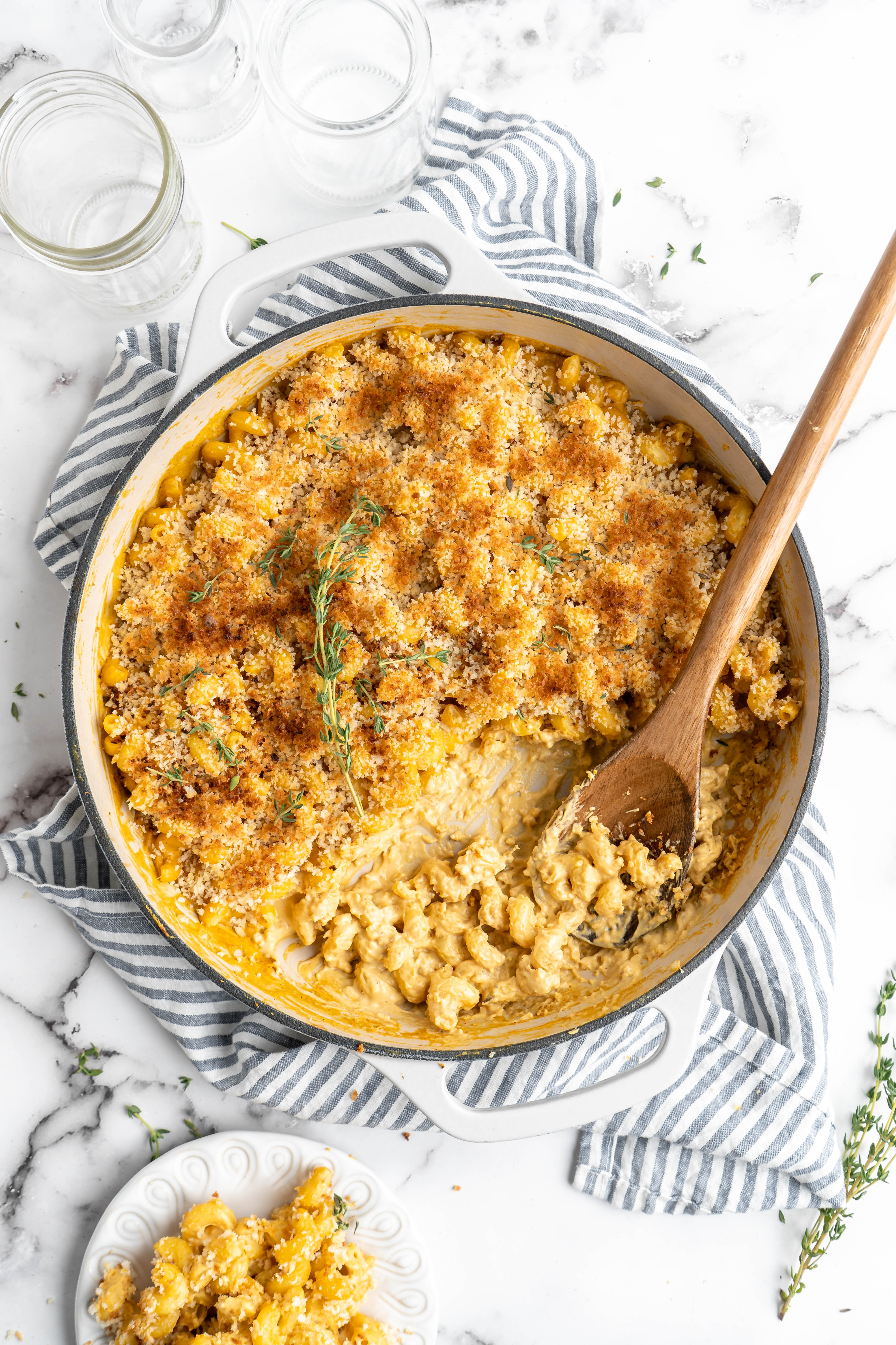 Baked vegan mac and cheese in skillet with wooden spoon, using nutritional yeast as a dairy substitute