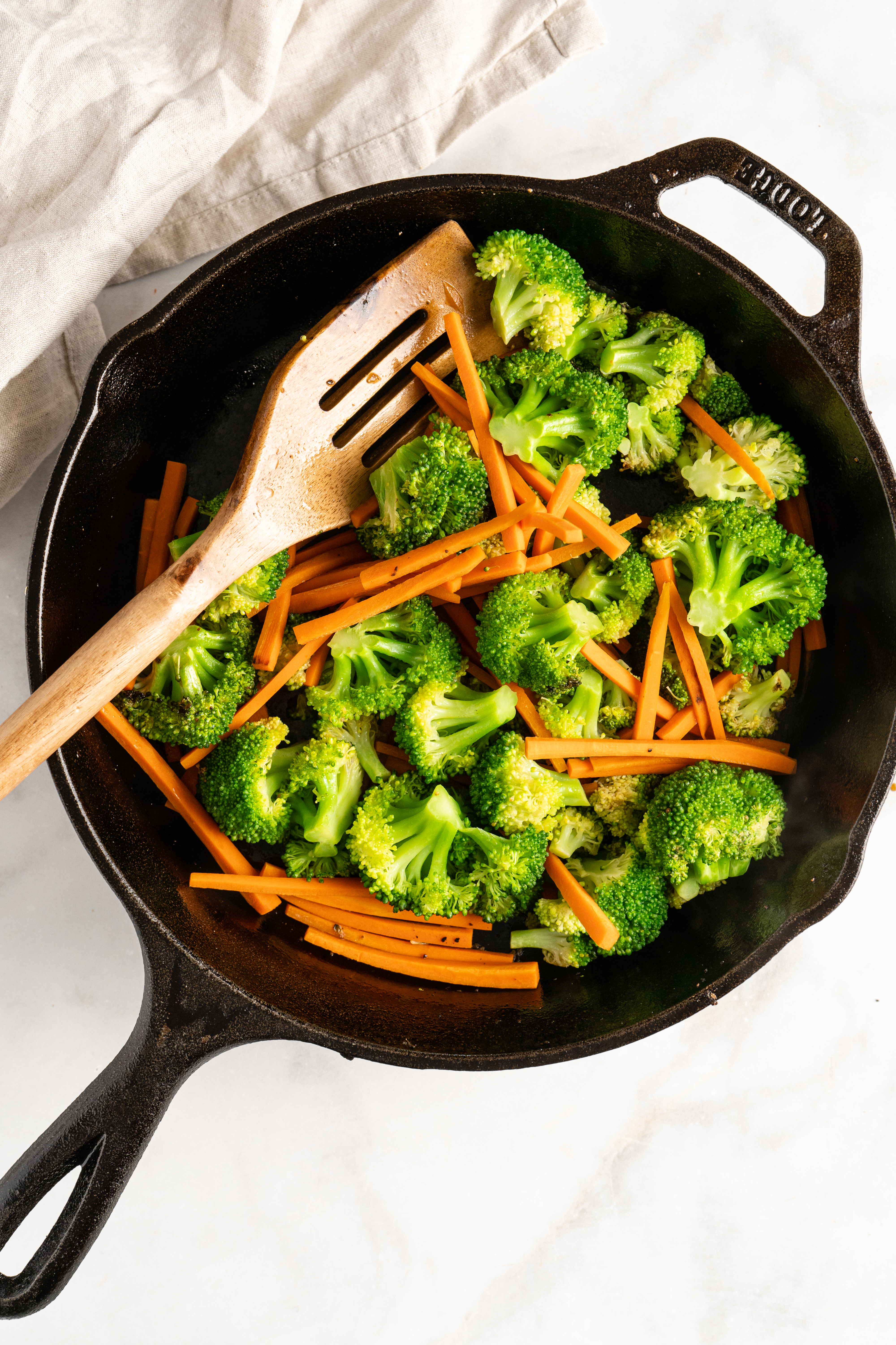 Overhead view of carrots and broccoli in cast iron skillet