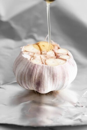 Pouring oil onto cut head of garlic