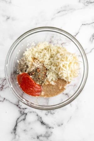 Ingredients for cauliflower pizza bites in glass bowl