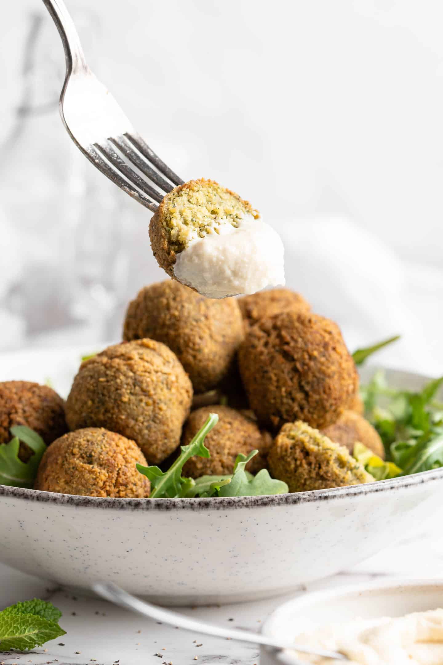 Falafel on a fork with tahini sauce