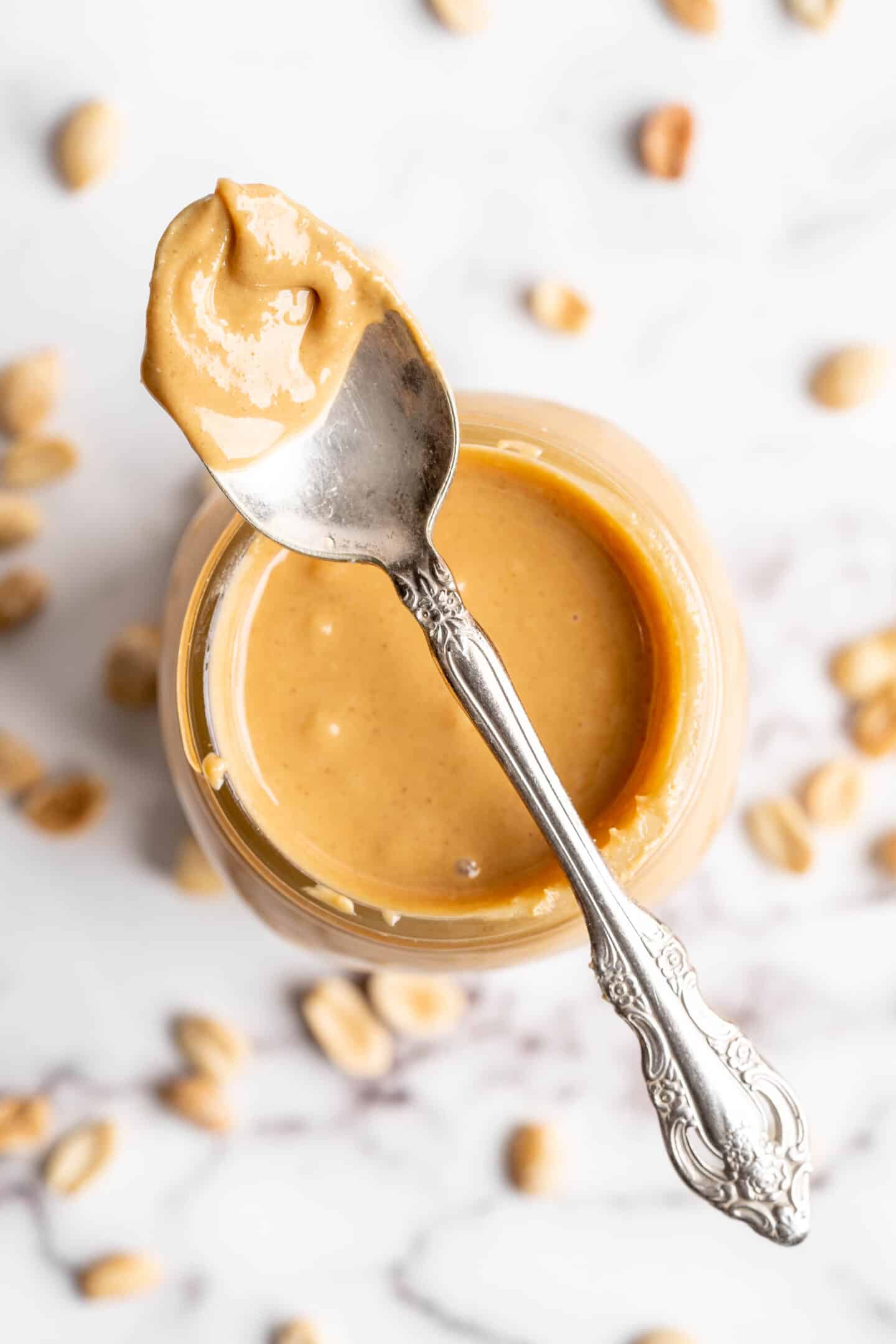 Overhead view of spoon of peanut butter set on jar