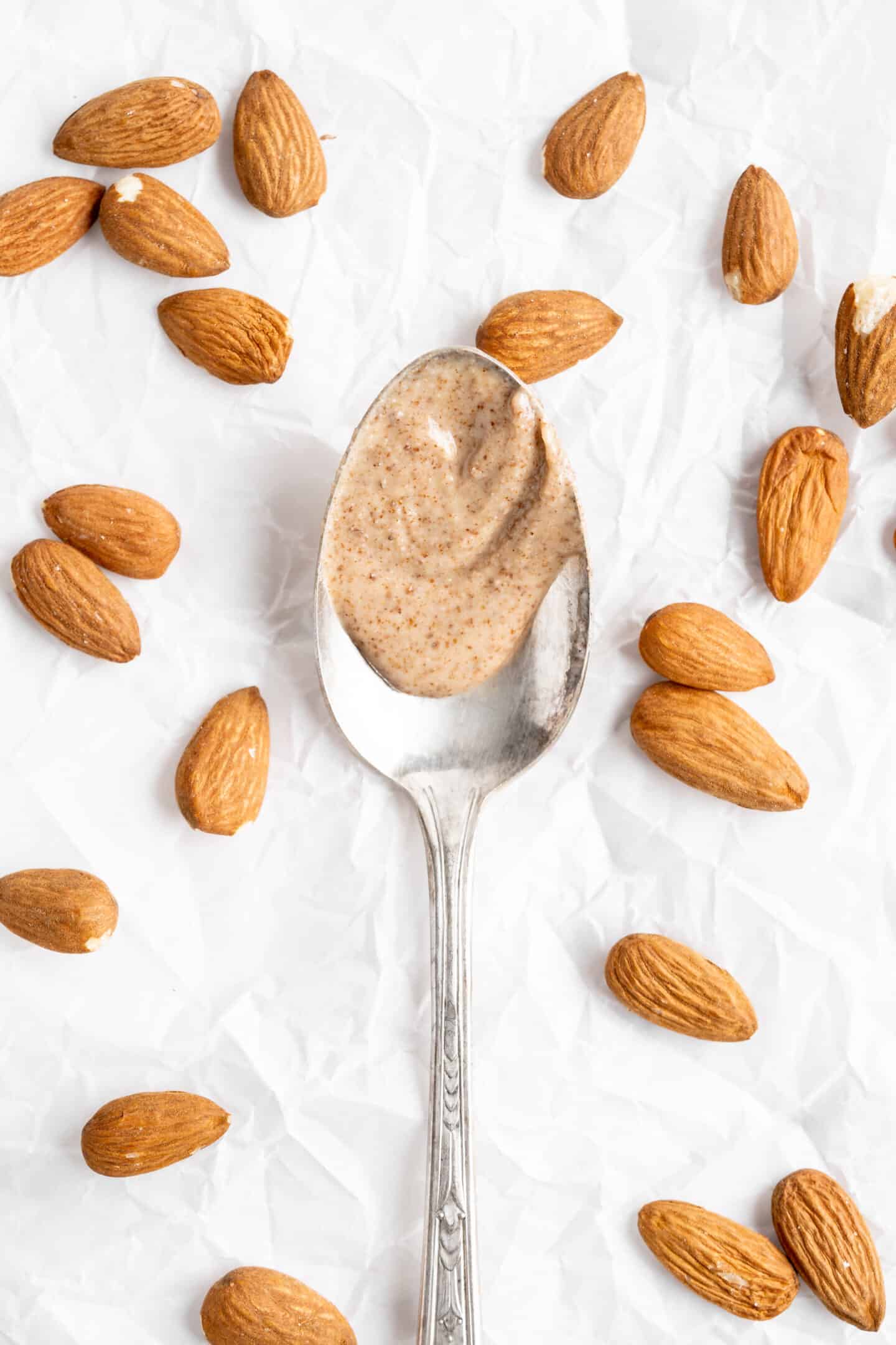 Almond butter on spoon with almonds surrounding it