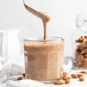 Spoon drizzling almond butter into jar