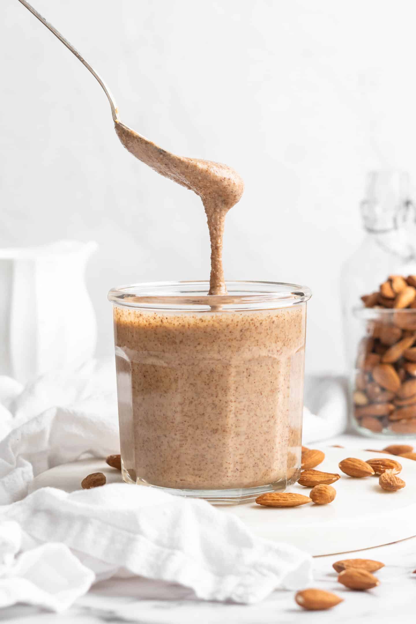 Spoon drizzling almond butter into jar