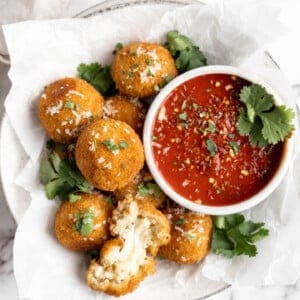 Vegan arancini in parchment-lined bowl with marinara sauce