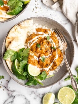 Vegan butter chicken in bowl with rice, naan, and garnishes
