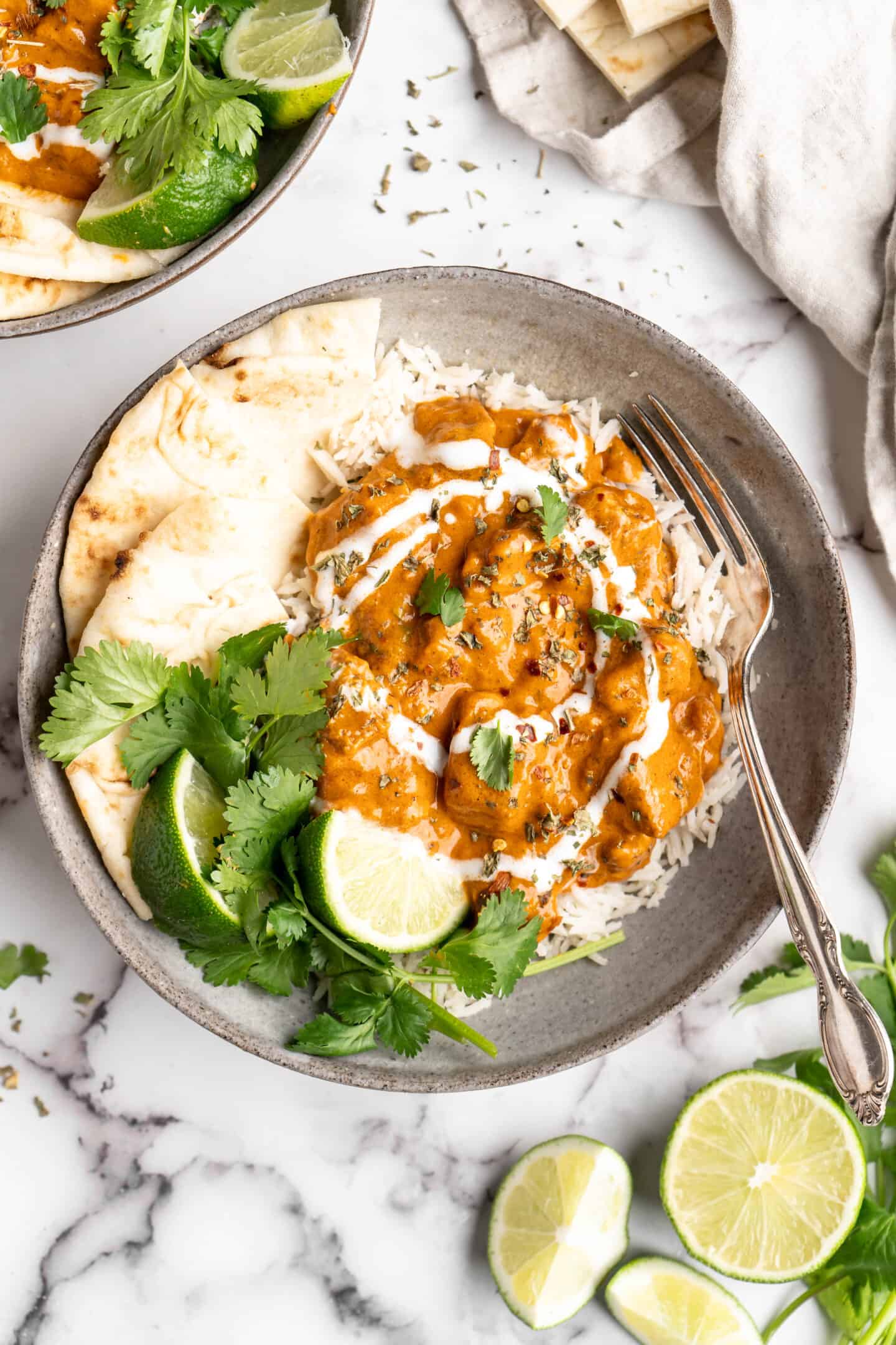Vegan butter chicken in bowl with rice, naan, and garnishes