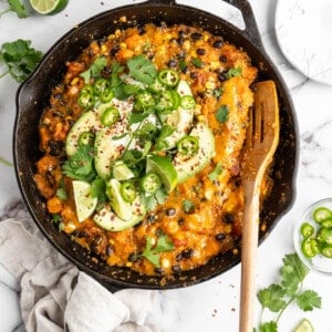 Vegan enchilada skillet with garnishes and serving spoon