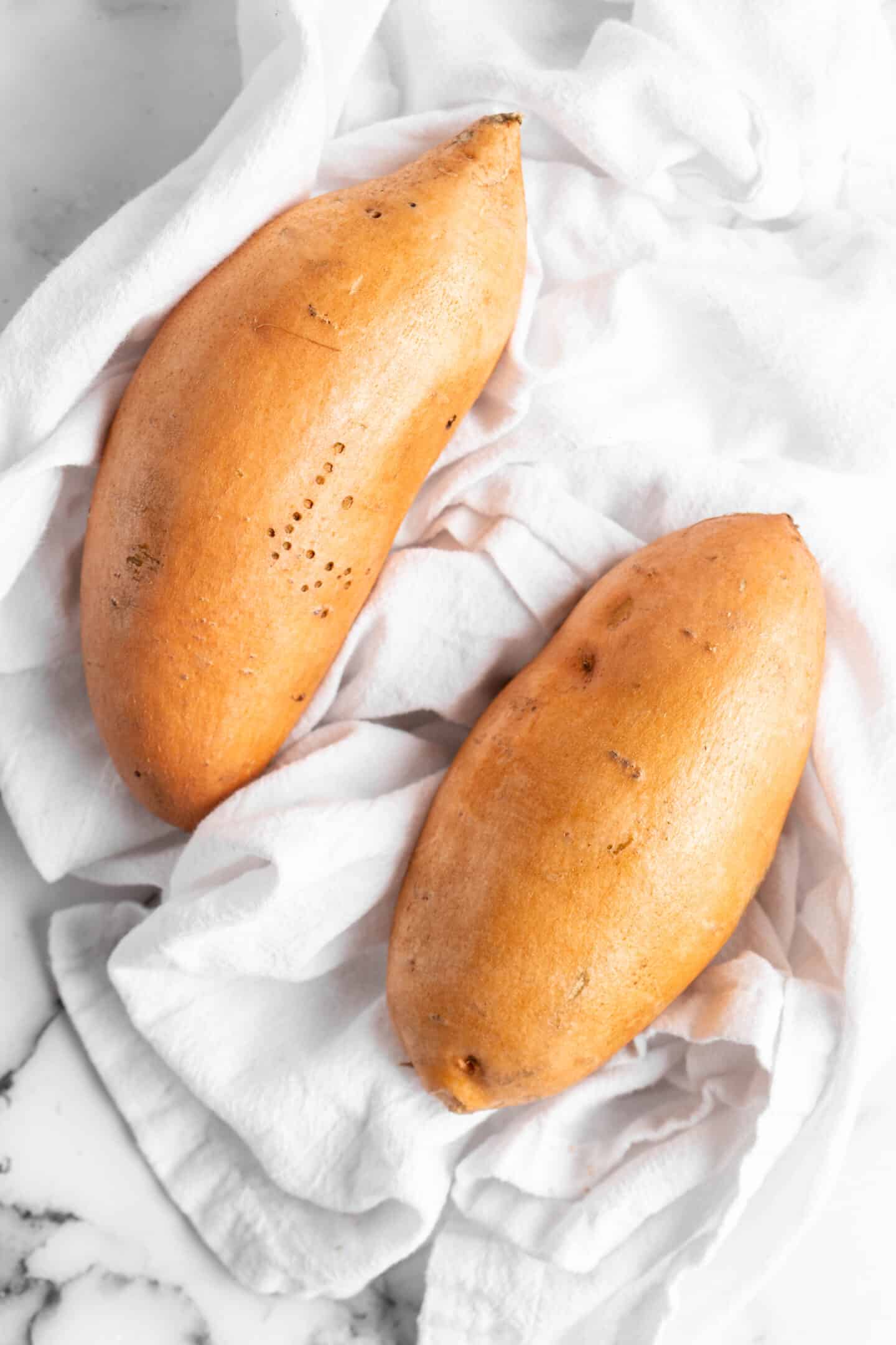 Two sweet potatoes on kitchen towel