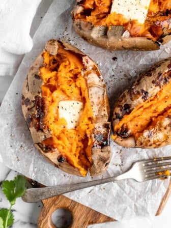 Overhead view of air fryer baked sweet potatoes topped with pat of butter