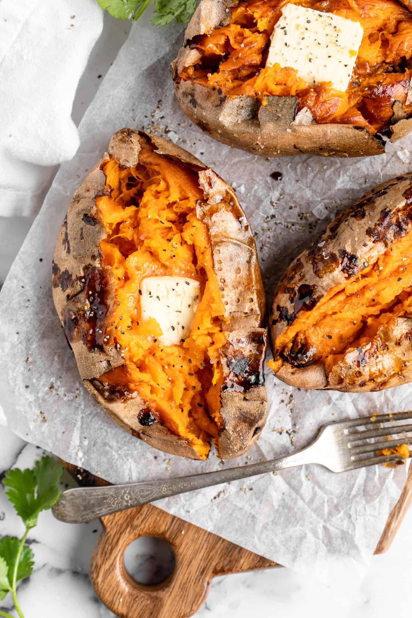 Overhead view of air fryer baked sweet potatoes topped with pat of butter