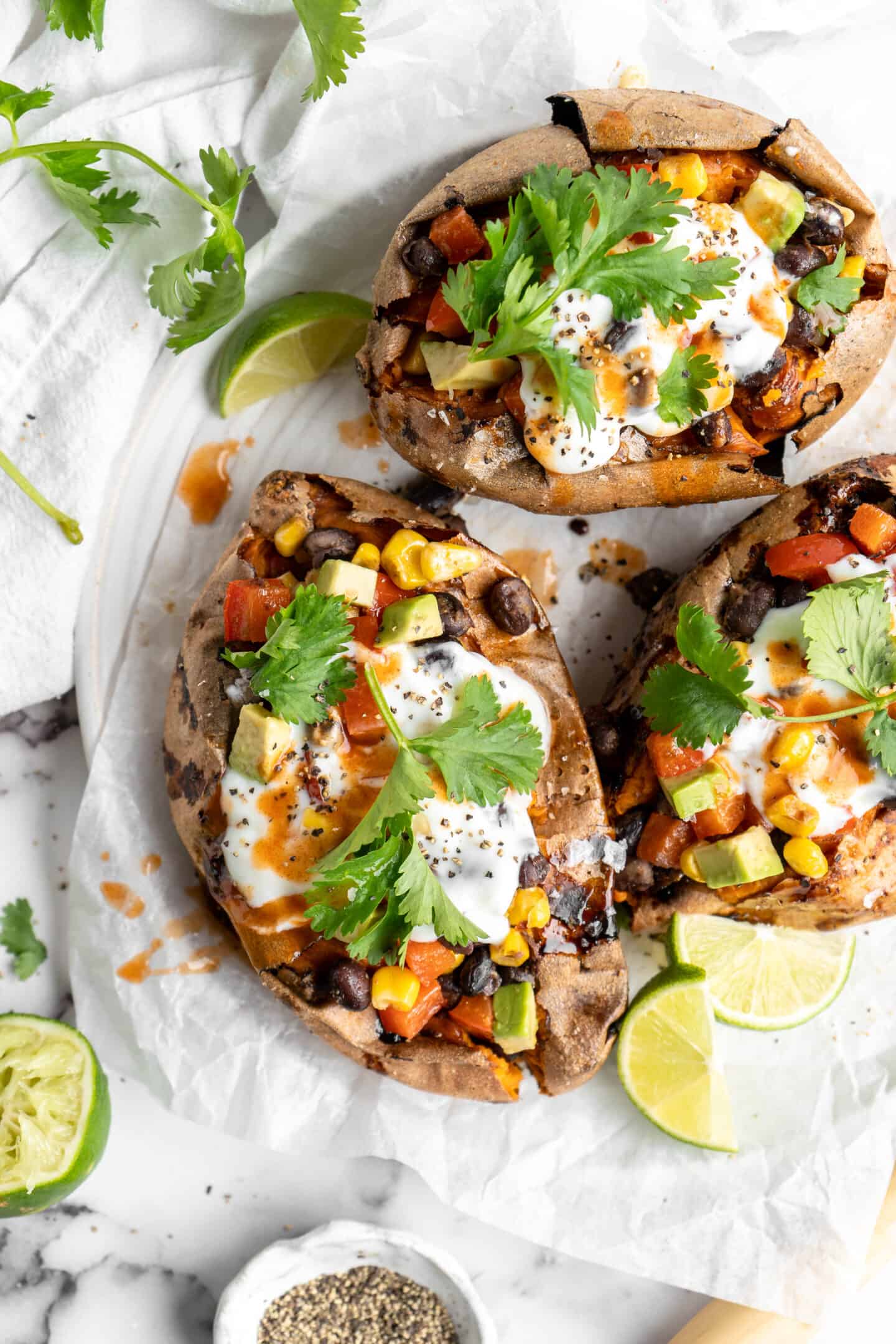 Overhead view of loaded air fryer sweet potatoes on plate with lime wedges