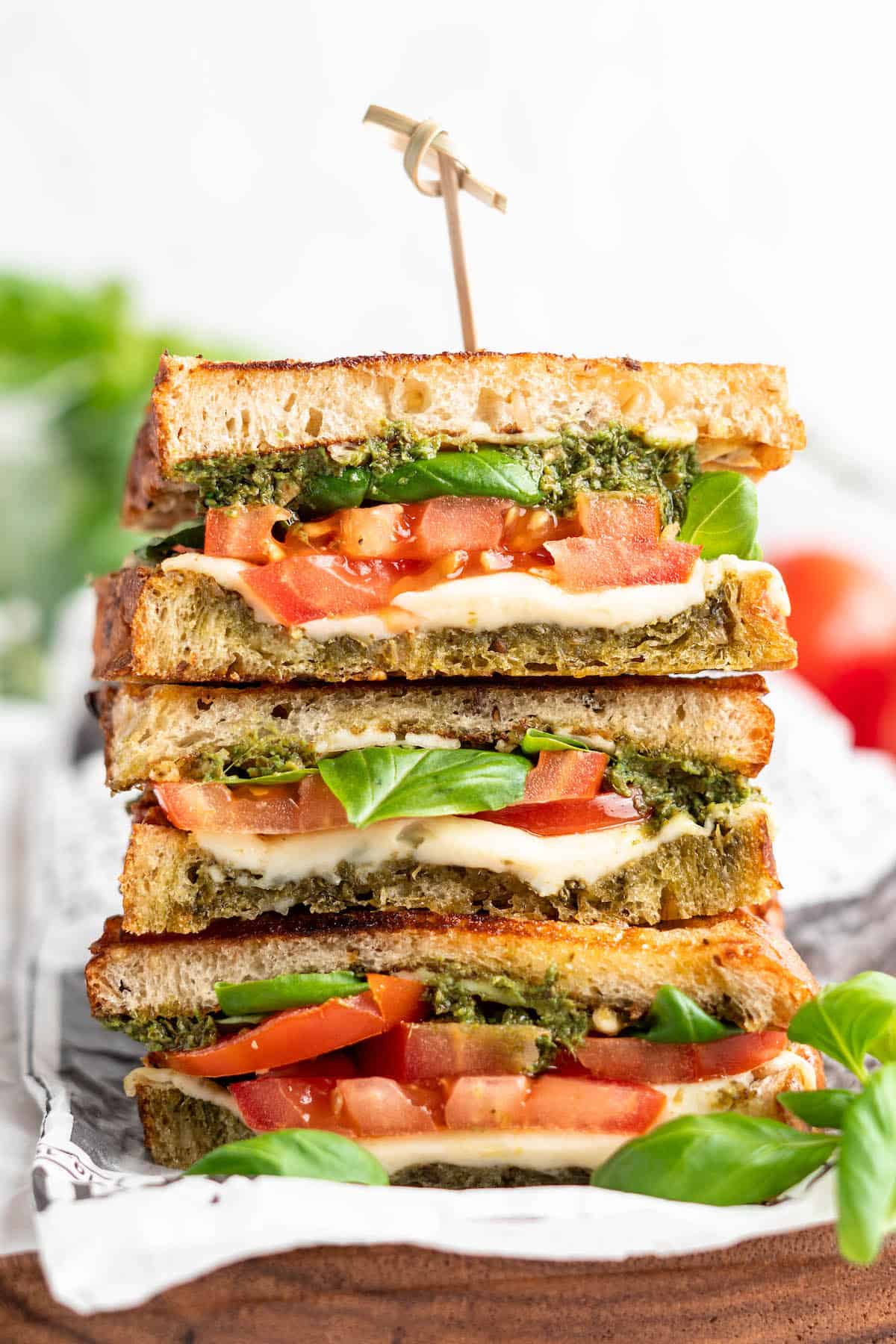 Three stacked vegan caprese sandwiches, cut to show layers of ingredients inside
