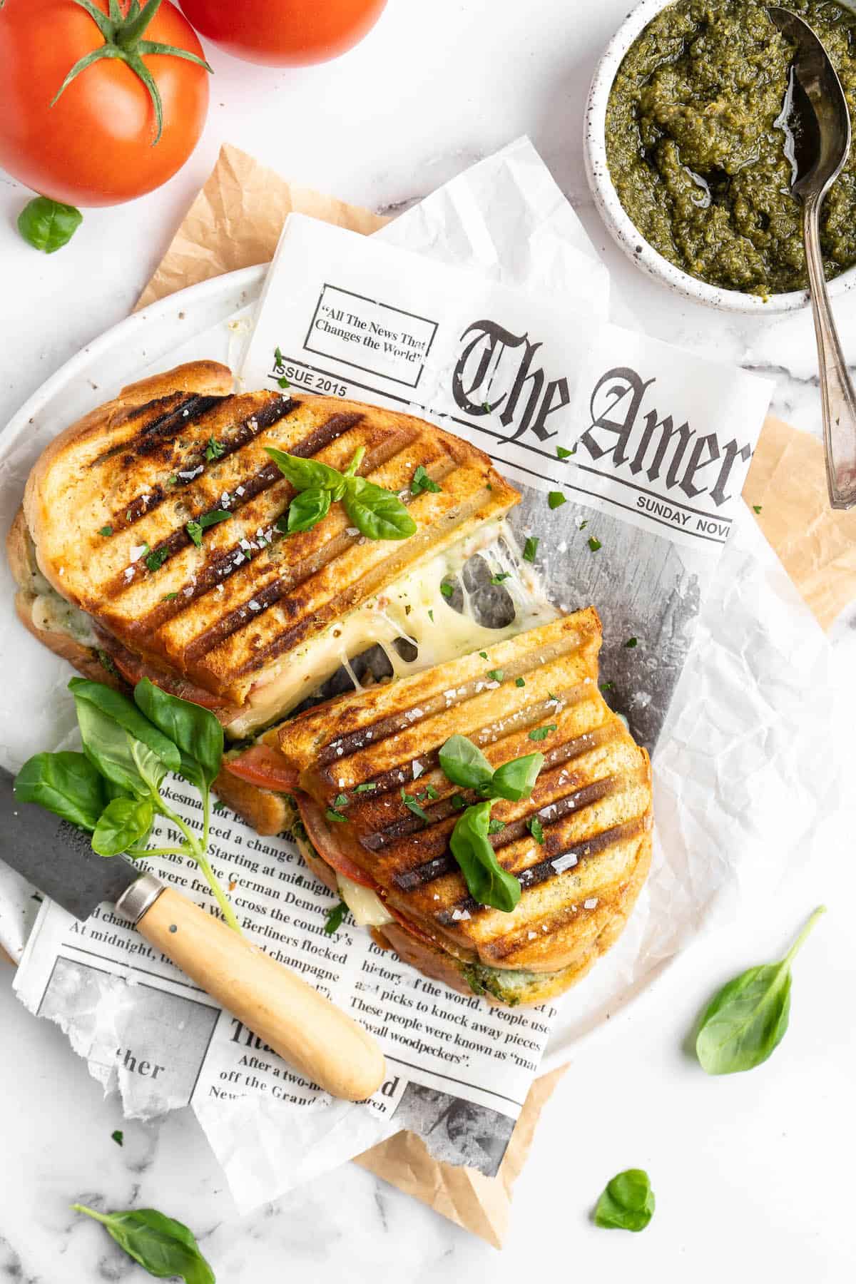 Halved vegan caprese panini, pulled apart to show stretching cheese