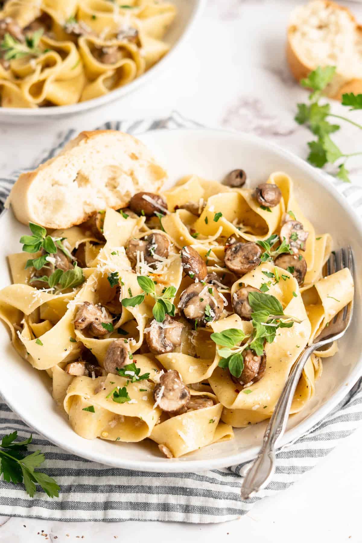Creamy Garlic Mushroom Pasta in white bowl with fork and slice of bread