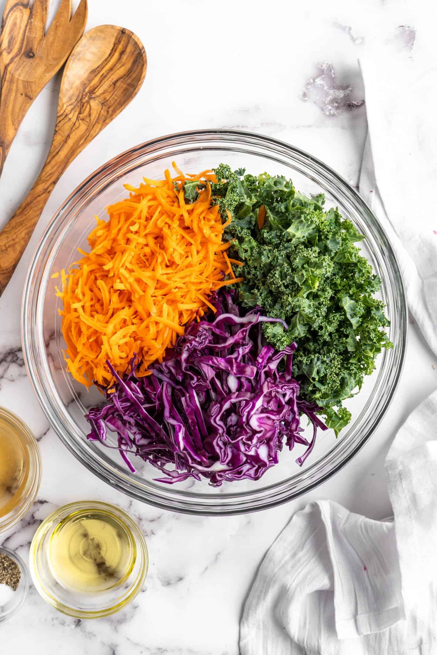 Overhead view of coleslaw ingredients in large glass mixing bowl