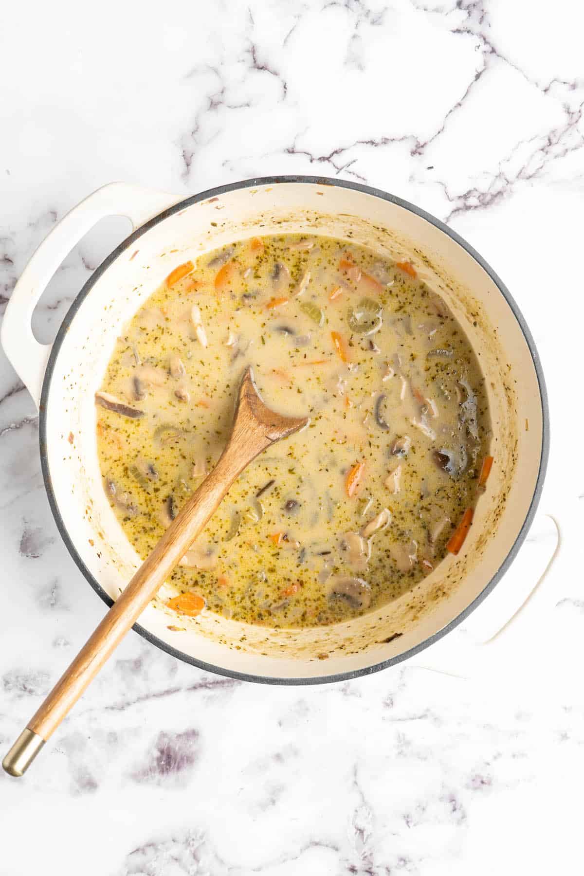 Overhead view of vegan mushroom wild rice soup in pot with wooden spoon